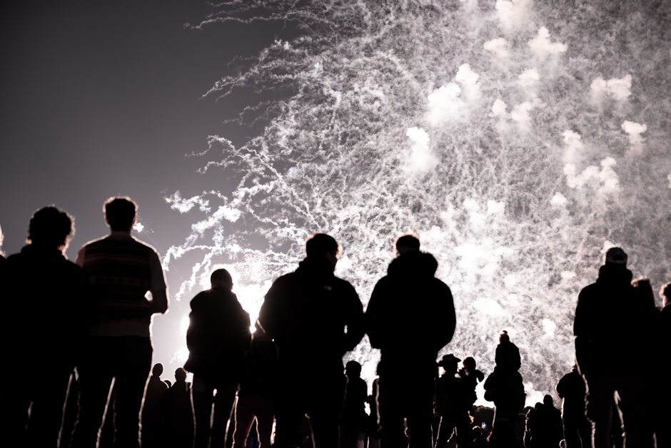 Enfants tenant des cierges magiques devant des feux d'artifice un soir d'automne