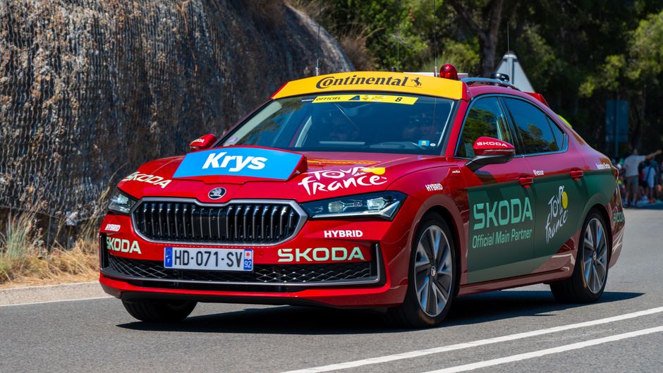 Peloton du Tour de France en course sur une route de campagne bordée de spectateurs